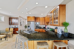 A modern kitchen with granite countertops, wooden cabinets, and a central island with bar stools.