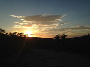A sunset over a desert landscape with sparse vegetation. - Secluded rental on 40 acre ranch. (Warner Springs)