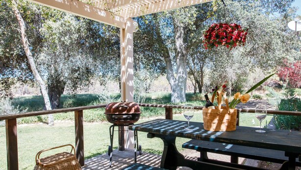 An outdoor patio with a wooden table, a grill, and a basket. - Secluded rental on 40 acre ranch. (Warner Springs)
