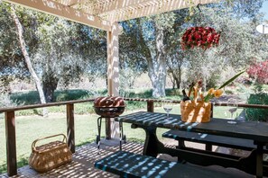 An outdoor patio with a wooden table, a grill, and a basket. - Secluded rental on 40 acre ranch. (Warner Springs)