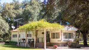 A single-story house with a porch, a satellite dish, and a large tree in the background. - Secluded rental on 40 acre ranch. (Warner Springs)