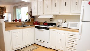 A kitchen with white cabinets, a stove, a sink, and a microwave. - Secluded rental on 40 acre ranch. (Warner Springs)