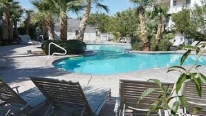 Un área de piscina con sillas de descanso y palmeras.
