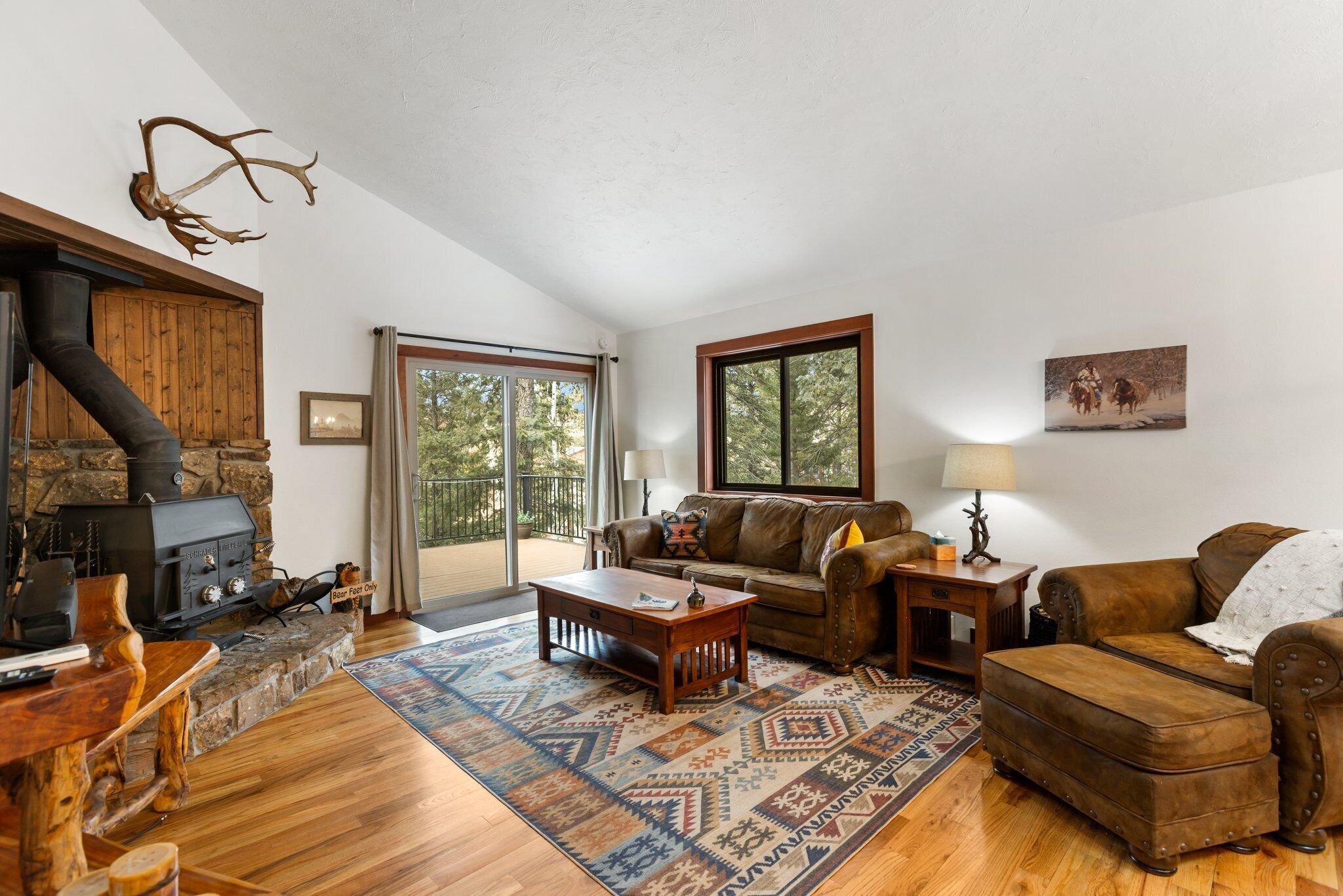 Un salon avec une cheminée en pierre, des meubles en bois et une grande fenêtre.