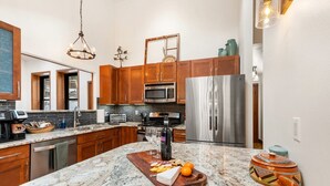 A kitchen with wooden cabinets, stainless steel appliances, a marble countertop, and a wooden cutting board with food items. - Bear Paw Haven-nestled in the trees. Pet & family friendly. HOT TUB, Free WiFi (Woodland Park)