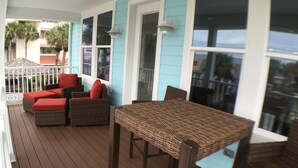A covered outdoor seating area with wicker furniture and a table, overlooking a residential area. - Steps to the non-driving section of the beach!  (Saint Augustine Beach)