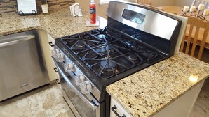 A kitchen with a stainless steel stove, granite countertop, and a dishwasher.