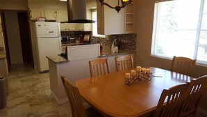 A kitchen with a dining table, chairs, a refrigerator, a microwave, and a stove.