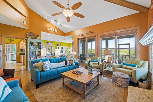 A spacious living room with a blue sofa, a wooden coffee table, and a ceiling fan.