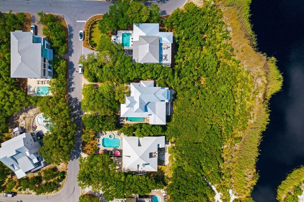 Vista aèria d'una zona residencial amb diverses cases, piscines i una gran massa d'aigua.