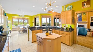 Una cocina luminosa con armarios de madera, una isla central y un comedor con vistas.