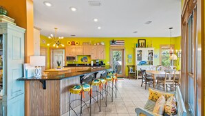 Una cocina con barra, armarios de madera y una mesa de comedor con sillas.