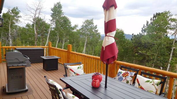 A deck with a table, chairs, a grill, and an umbrella. - Secluded mountain cabin in the woods (Jefferson)