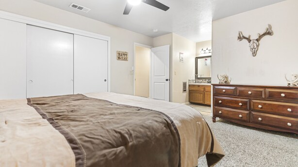 A bedroom with a bed, a dresser, a ceiling fan, and a wall-mounted deer skull decoration. - A View Above the Pines at Pine Mountain Lake (Groveland)