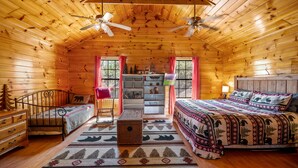 A cozy log cabin bedroom with a bed, a desk, and a chair. - Wooded Cabin · Private Hot Tub · Pet-Friendly · Near Pigeon Forge (Sevierville)