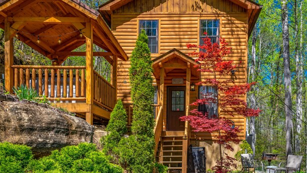 A wooden cabin with a porch and a staircase leading to the entrance. - Wooded Cabin · Private Hot Tub · Pet-Friendly · Near Pigeon Forge (Sevierville)