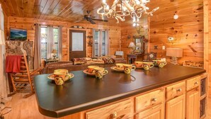 A wooden cabin interior with a large dining table, wooden cabinets, and a chandelier. - Wooded Cabin · Private Hot Tub · Pet-Friendly · Near Pigeon Forge (Sevierville)