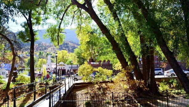 Un parque con un puente, árboles y un edificio con un cartel que dice 'CINEMA'.