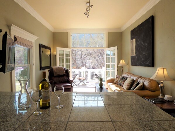 A living room with a fireplace, a dining area with a table and chairs, and a view of the outdoors through large windows.