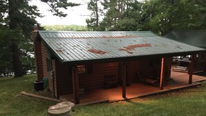 A rustic cabin with a metal roof, a porch, and a small deck area.