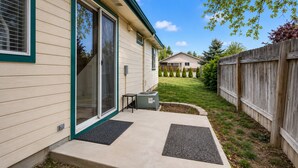 Einbungalow mit überdachter Terrasse, einer Glastür und einer kleinen Sitzgelegenheit im Freien.