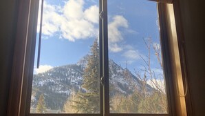 Une fenêtre donnant sur un paysage de montagnes et de forêts.