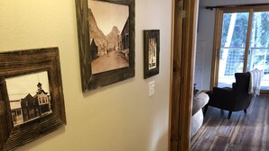Un couloir avec un plancher en bois, un canapé et des tableaux encadrés accrochés au mur.