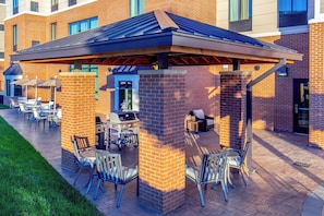 An outdoor patio area with brick pillars, metal chairs, and a grill station. - Staybridge Suites Charlottesville Airport by IHG (Charlottesville)