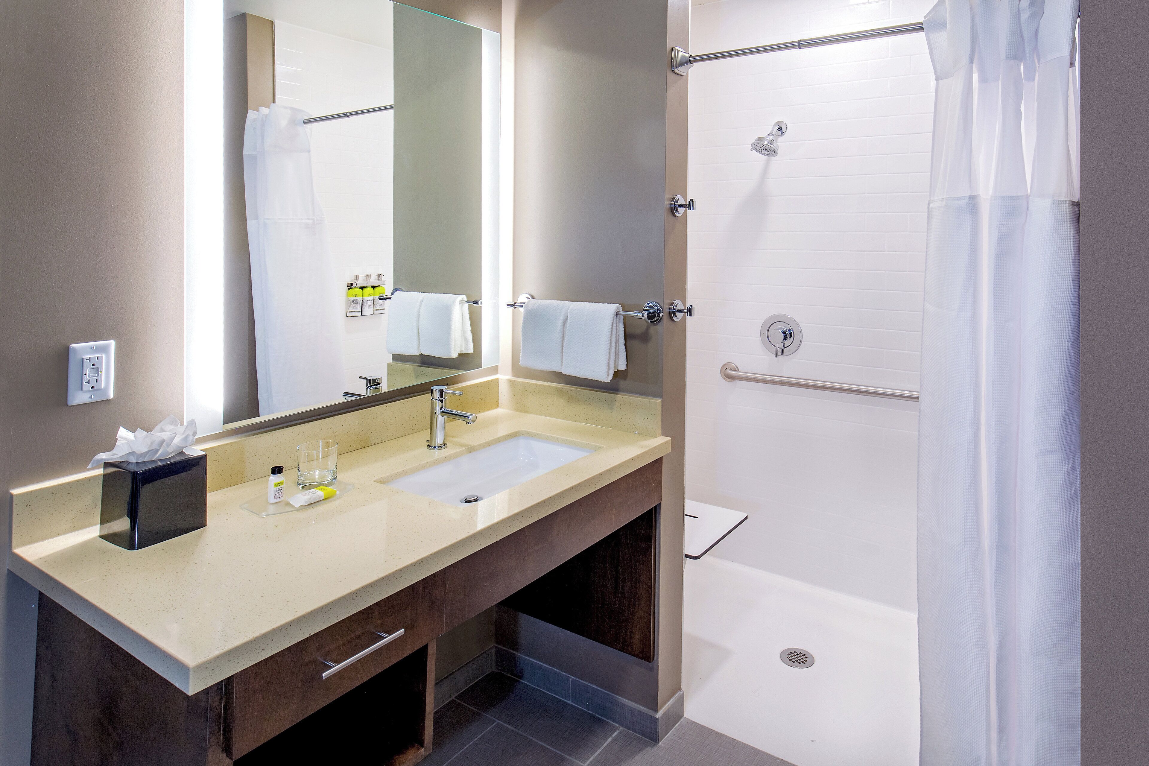 A bathroom with a sink, mirror, towel rack, and shower.