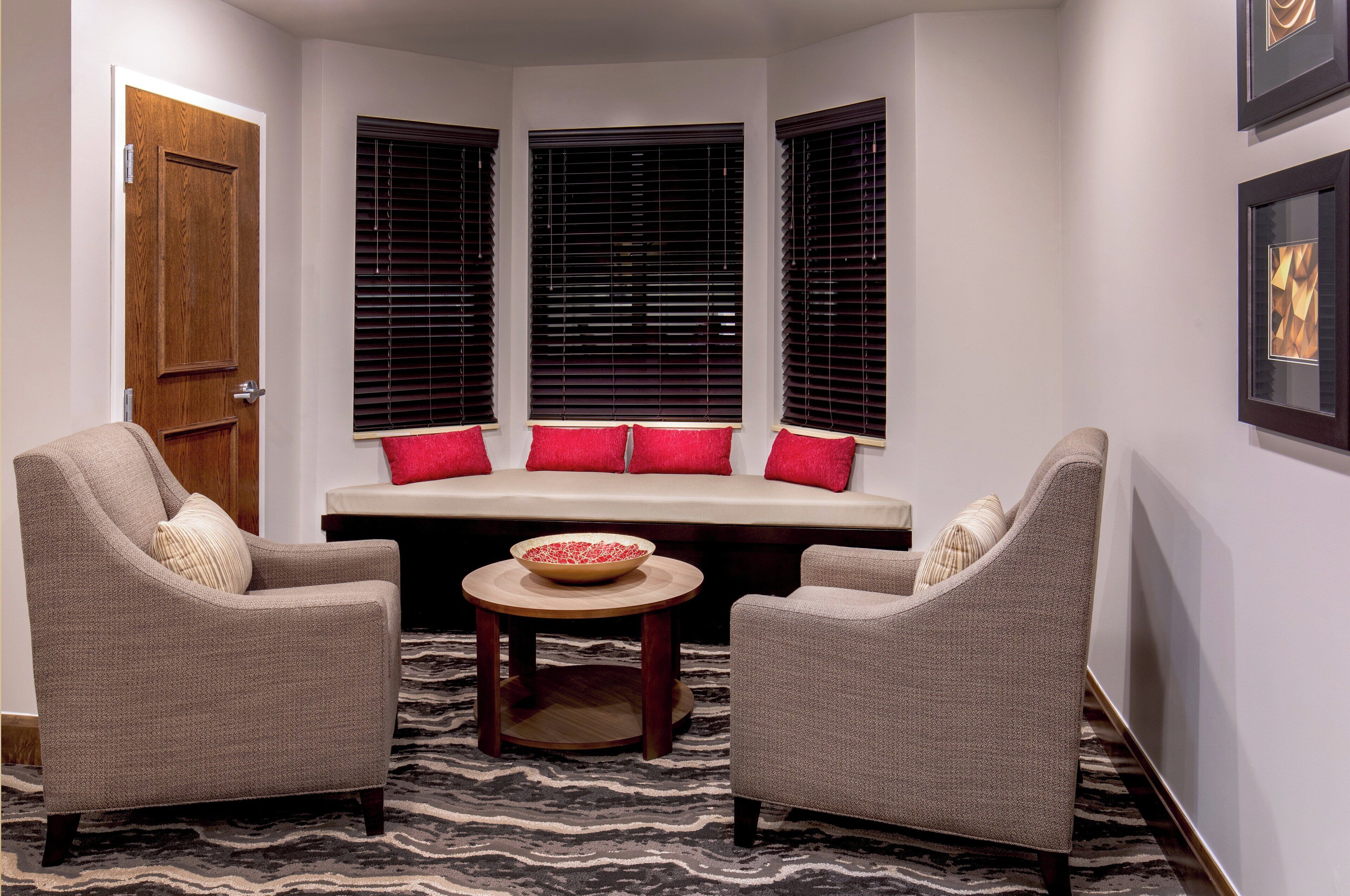 A corner seating area with two armchairs, a bench with red cushions, and a small table with a bowl.