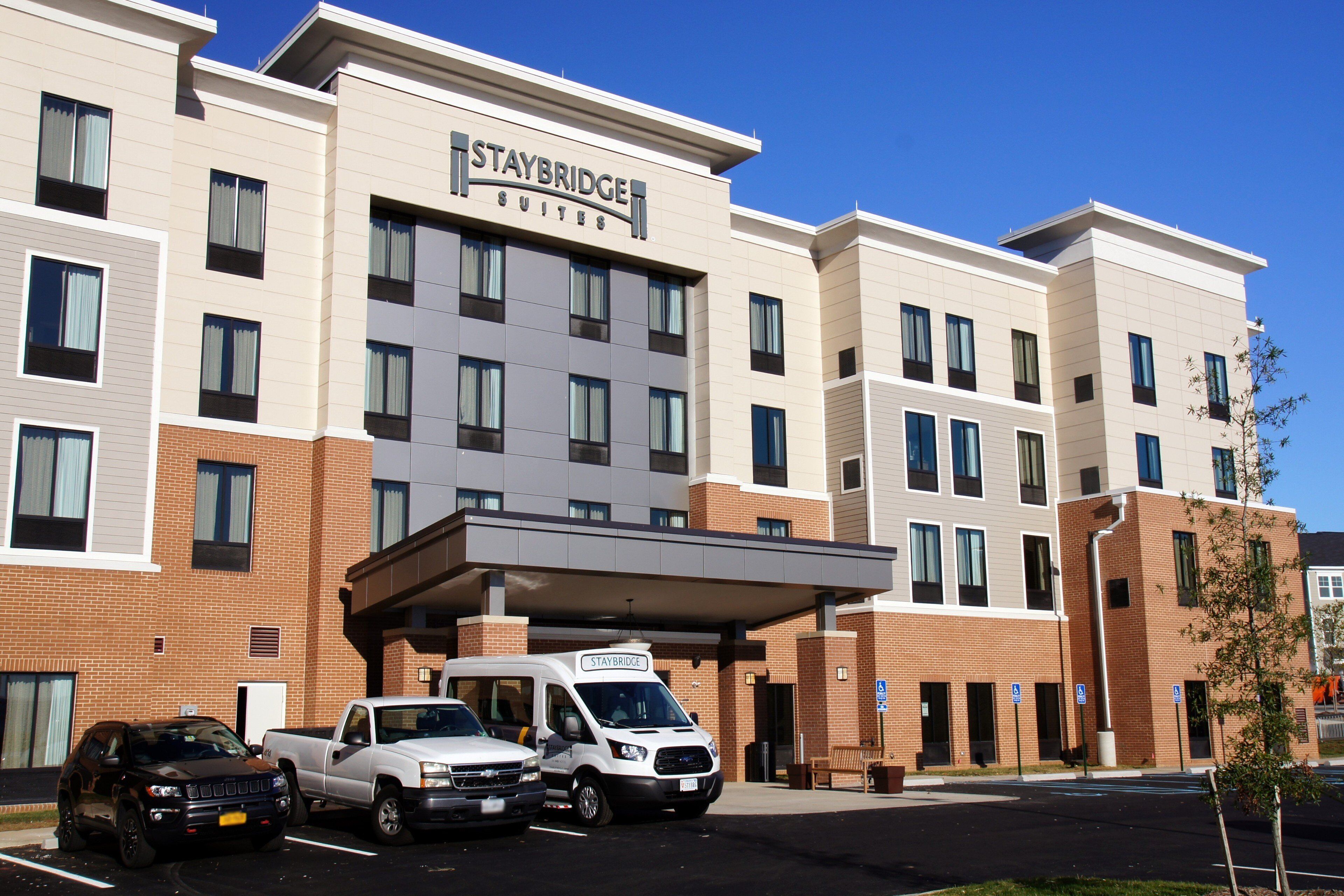 Ein Staybridge Suites Hotel mit Backsteinfassade, zahlreichen Fenstern und einem überdachten Eingang.