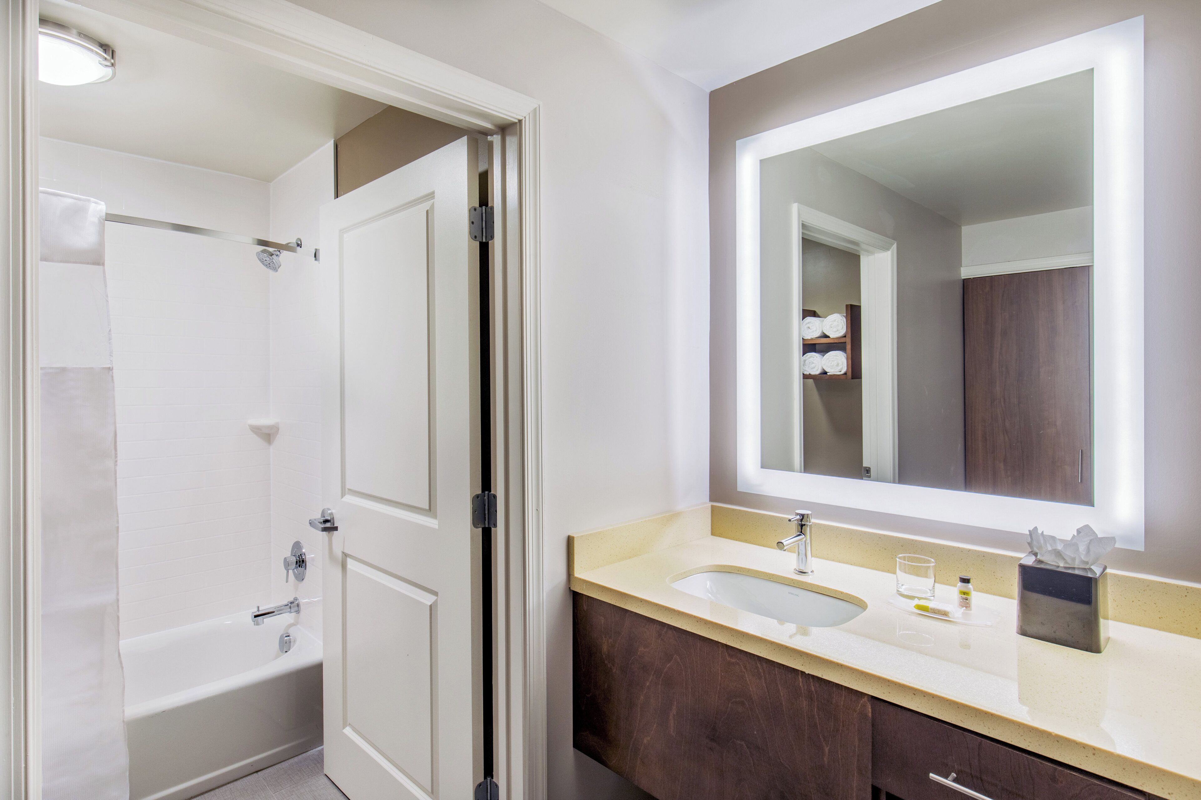 Un baño con bañera, lavamanos, espejo y un perchero para toallas.
