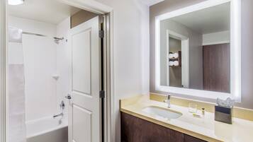 Un baño con bañera, lavamanos, espejo y un perchero para toallas.