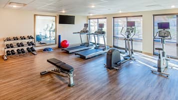 Une salle de sport équipée de tapis de course, d’un banc de musculation, d’haltères et d’un vélo d’appartement.