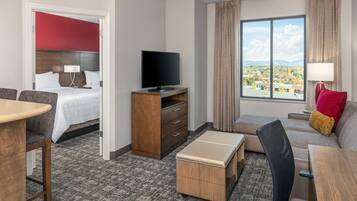 Habitación de hotel con cama, televisión, escritorio, sofá y ventana con vistas.