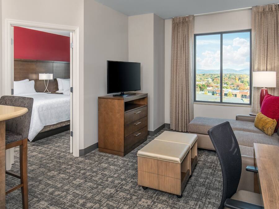 Habitación de hotel con cama, televisión, escritorio, sofá y ventana con vistas.