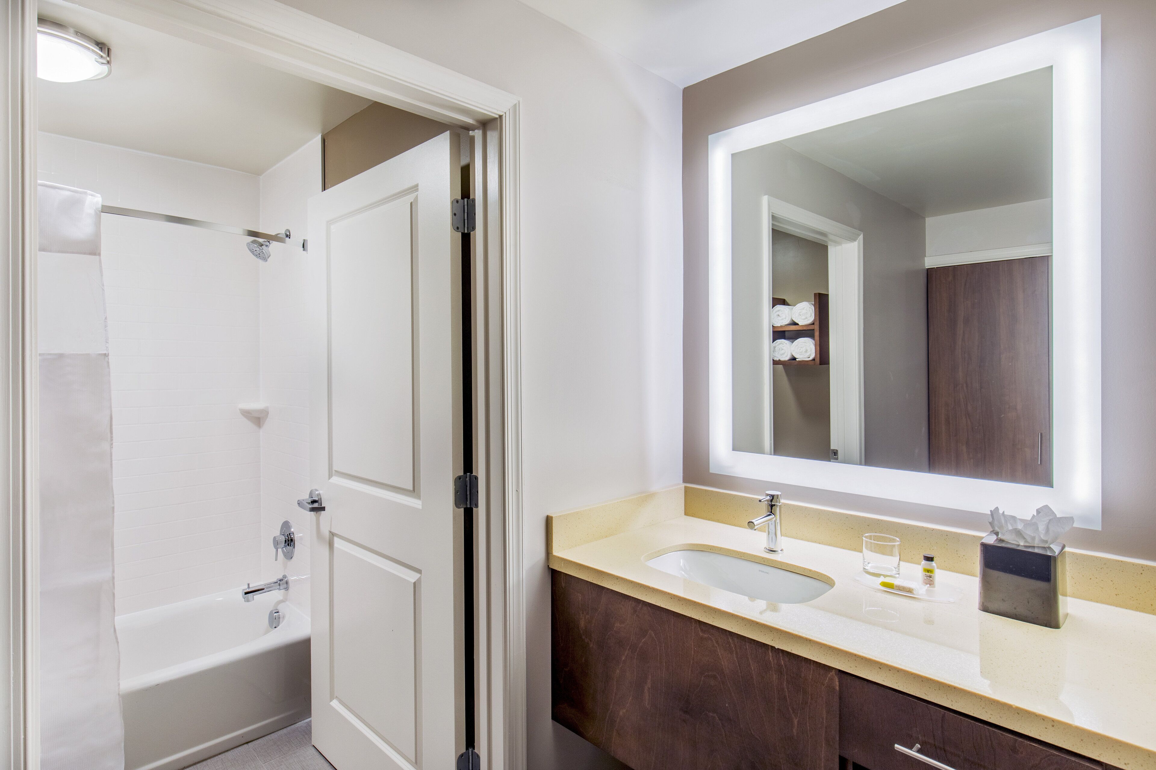 A bathroom with a bathtub, a sink, and a large mirror.