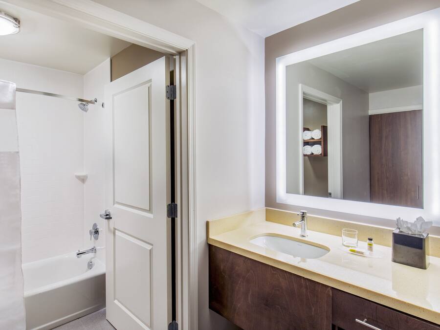 A bathroom with a bathtub, a sink, and a large mirror.