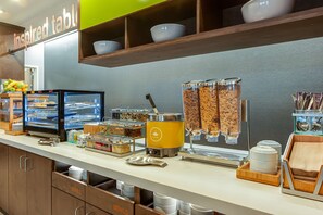 Ein reichhaltiges Buffet mit verschiedenen Speisebehältern, einer Kaffeemaschine und einem Schild mit der Aufschrift 'inspired table'.