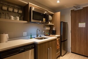 A modern kitchen with stainless steel appliances, a dishwasher, and a wooden cabinet.