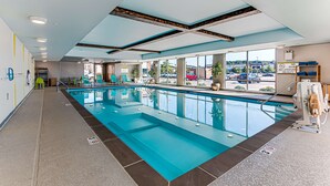 A modern indoor pool with clear glass walls, a blue pool, and a lifeguard chair. - Home2 Suites by Hilton Nashville Bellevue (Nashville)