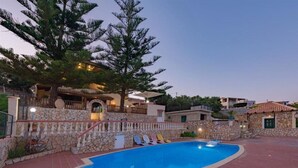 A swimming pool with a stone wall and a stone staircase leading to a building. - Kefalonian 360° Sunrise (Kefalonia)