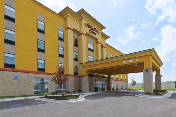 Un hôtel Hampton Inn avec une façade jaune, une entrée accueillante et un parking.