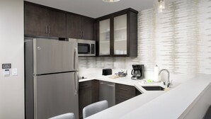 A modern kitchen with stainless steel appliances, dark wood cabinets, a white countertop, and a hanging light fixture. - Residence Inn by Marriott Modesto North (Modesto)