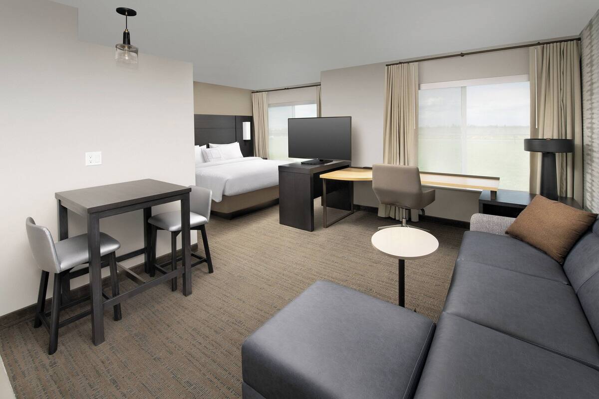 A hotel room with a bed, a desk with a computer, a sofa, and a TV.