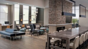 A modern hotel lobby with a long dining table, sofas, and a stone accent wall. - Residence Inn by Marriott Modesto North (Modesto)