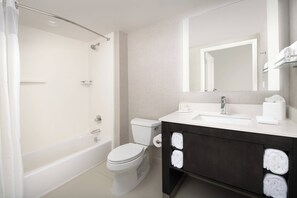 A modern bathroom with a bathtub, toilet, and vanity with towels.