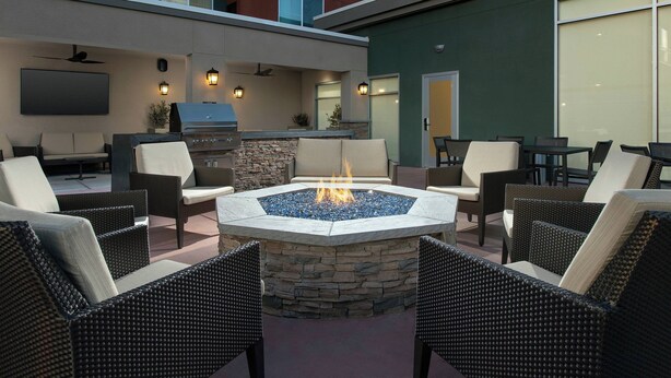An outdoor patio with a stone fire pit, wicker furniture, a grill, and a flat-screen TV. - Residence Inn by Marriott Modesto North (Modesto)