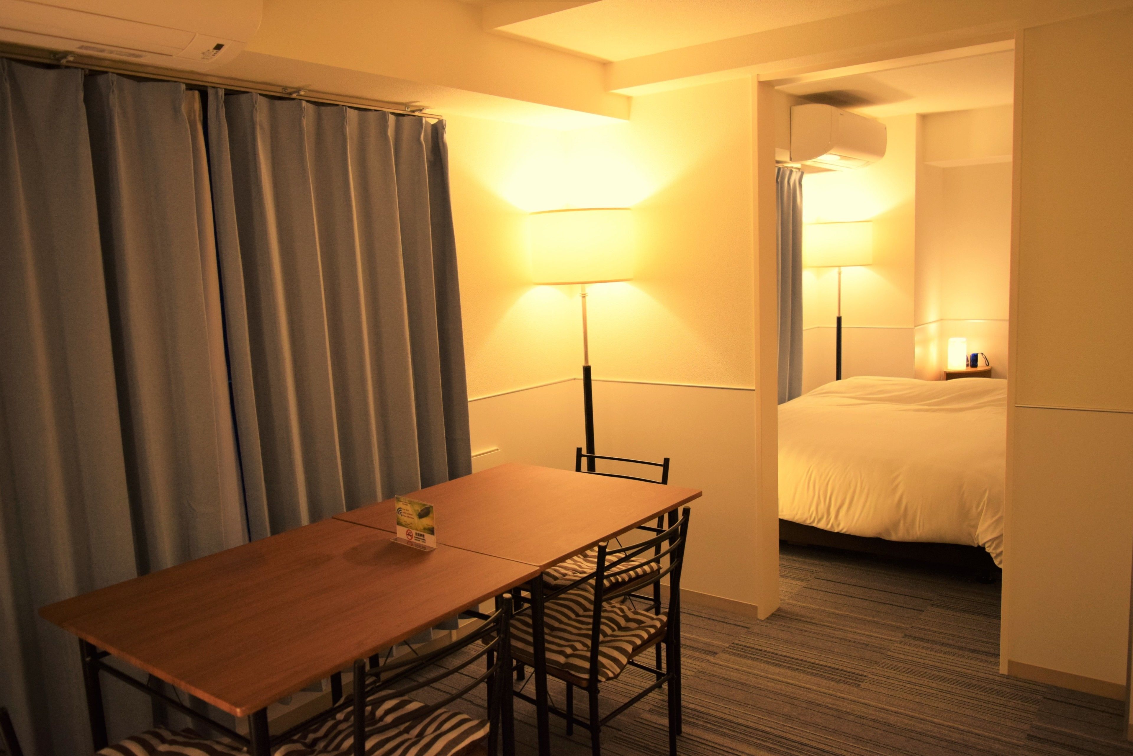 Una habitación de hotel con una mesa de madera, sillas a rayas de cebra, una cama y dos lámparas de noche.