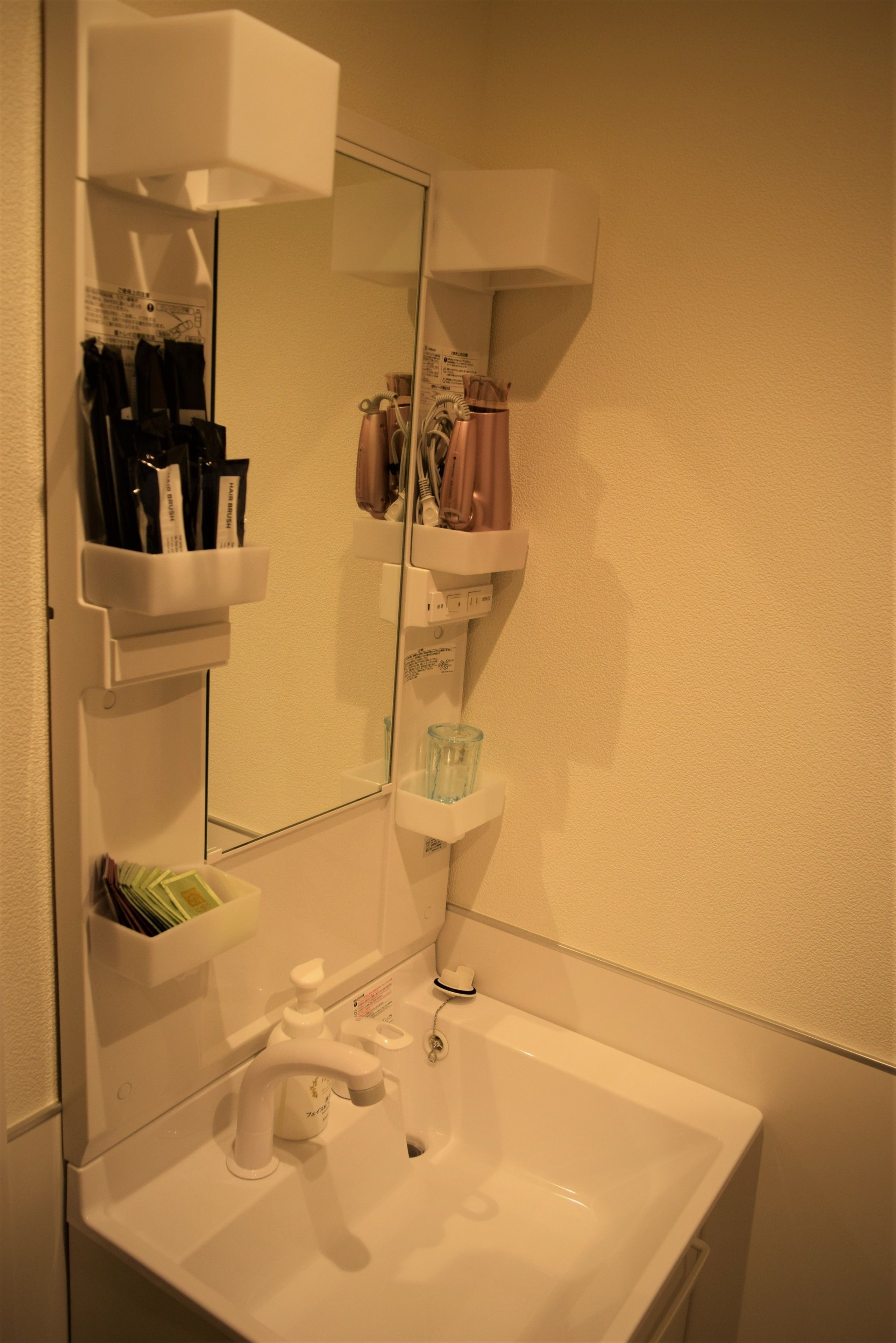 A bathroom with a white sink, a mirror, and shelves holding toiletries and a toothbrush.